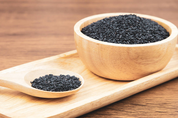 Black sesame seeds in a wooden spoon. - Photo, Image