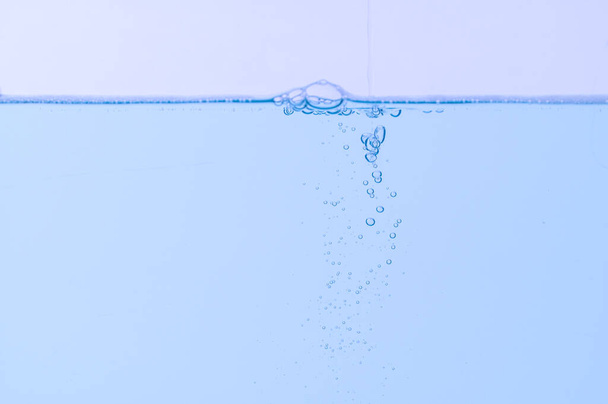 Jasnoniebieskie bąbelki i woda Białe tło - Zdjęcie, obraz