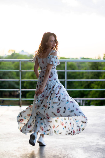 girl running in white dress on the terrasse, keeps the dresses edge - Photo, Image