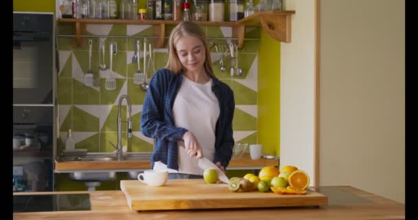 Jovem desfrutando de maçã verde cortada na cozinha
 - Filmagem, Vídeo