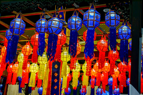 Closeup and look up view of decorated Thai Lanna style lanterns to hang on hotel lobby ceiling background with open lights on - Photo, Image