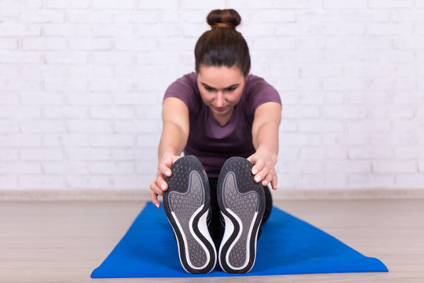 концепция здорового образа жизни - вид спереди молодой женщины, делающей упражнения на растяжку на коврике йоги
 - Фото, изображение