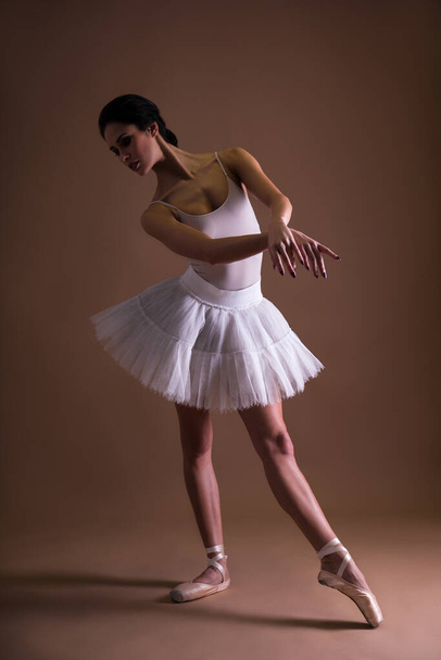 young beautiful woman ballerina in tutu posing over beige background - Photo, image