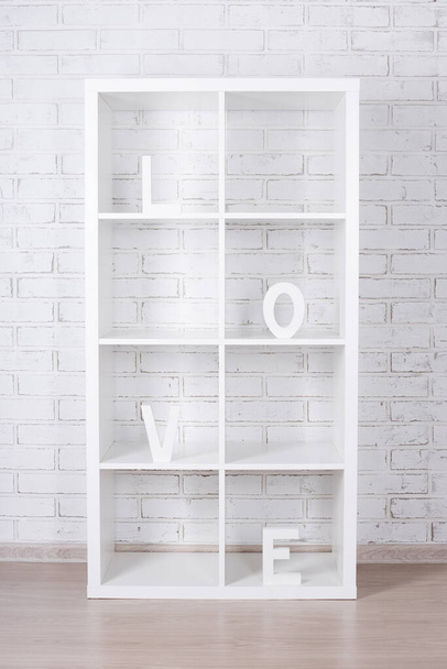 houten letters vormen woord LIEFDE in moderne plank over witte bakstenen muur achtergrond - Foto, afbeelding