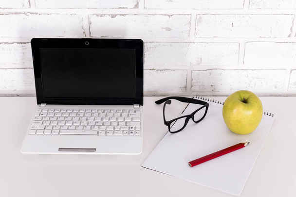 miejsce pracy w domu lub w biurze - biały nowoczesny laptop, okulary i notebook na stole - Zdjęcie, obraz