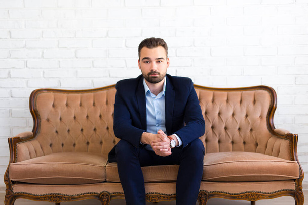 business and success concept - handsome bearded man sitting on vintage sofa - Photo, Image