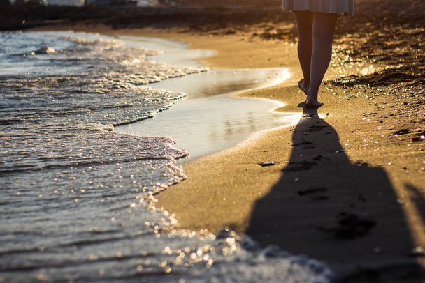 Пляжная концепция путешествия - женщина ходит по песчаному пляжу, оставляя следы на песке
 - Фото, изображение