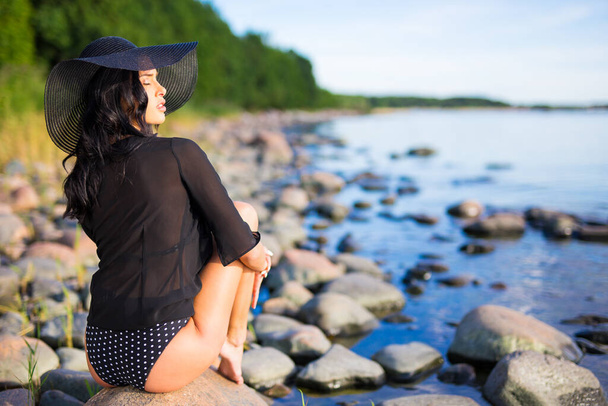 jovem modelo bonito sentado na praia rochosa
 - Foto, Imagem
