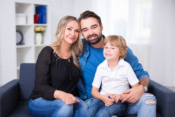 Mutlu aile portresi. Çift ve küçük oğlu evdeki koltukta oturuyor. - Fotoğraf, Görsel