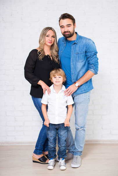 retrato de comprimento total da família casal e pequeno filho sobre parede de tijolo branco
 - Foto, Imagem