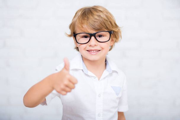 close up portrait of cute little boy in glasses thumbs up over white - 写真・画像
