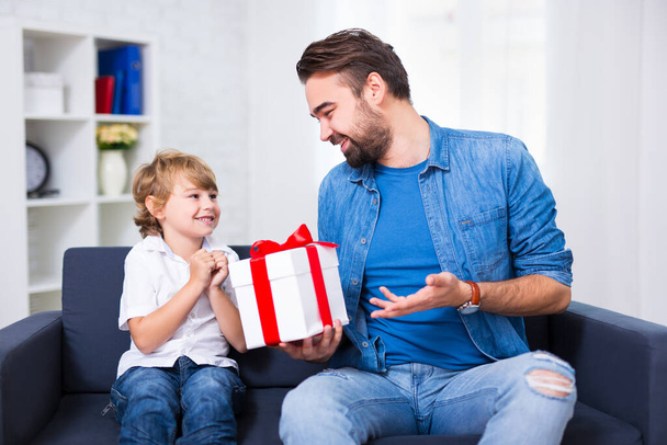 father's day or christmas concept - little son and his father with gift at home - Photo, Image