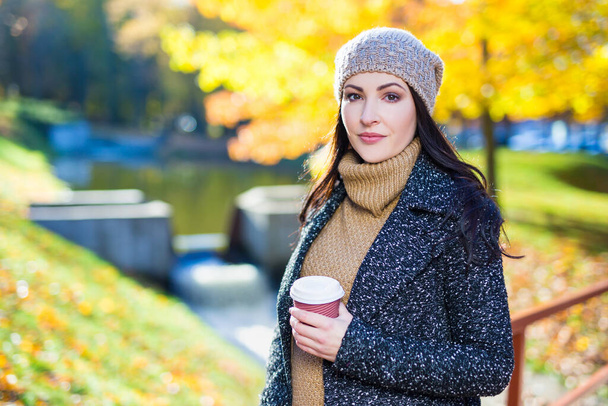 Güz parkında bir fincan kahveyle güzel bir kadının portresi. - Fotoğraf, Görsel