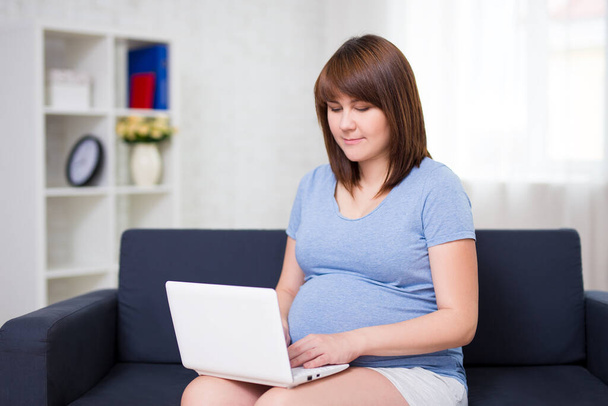 giovane bella donna incinta che utilizza il computer portatile a casa - Foto, immagini