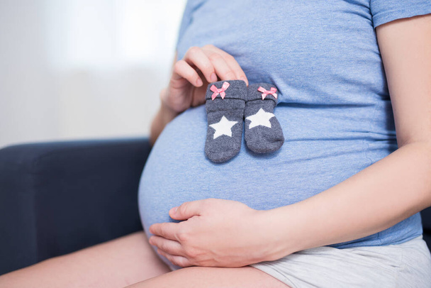 close up de barriga grávida e pequenas meias de bebê
 - Foto, Imagem
