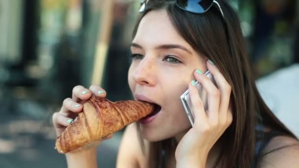 Woman talking on cellphone and eating croissant - Metraje, vídeo