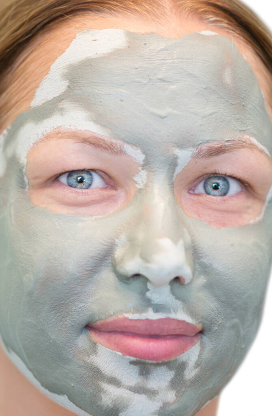 νεαρή όμορφη γυναίκα με πήλινη μάσκα στο πρόσωπό της - Φωτογραφία, εικόνα