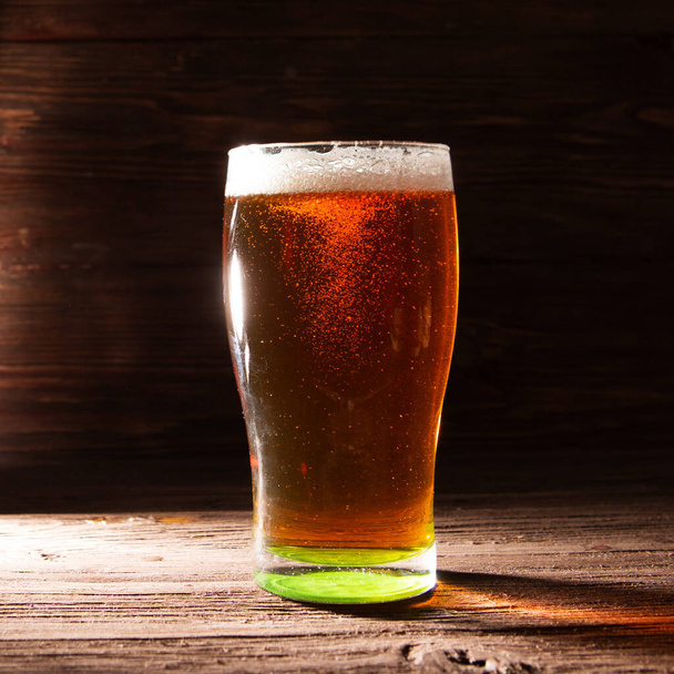 Glass of beer on brown wooden background - Фото, изображение
