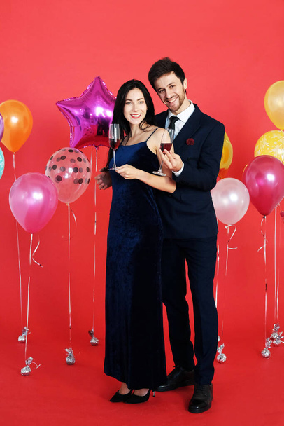 Sweet couple Love smile and spending Romantic with drinking wine in christmas time and celebrating new year eve, valentine day with colorful balloon on red background - Fotó, kép