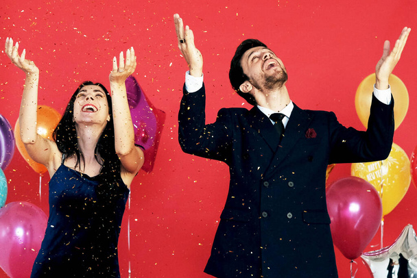 Couple love romantic Smile and dancing in Chrismas party, birthday time and celebration of New year eve and decoration with colorful ballons and  gold glitter sprinkle on red background - Photo, image