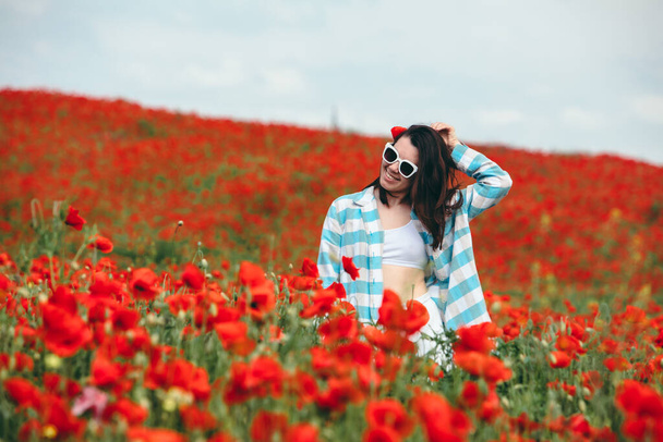 ケシの花の畑でサングラスをしてる若い女性。コピースペース。夏時間 - 写真・画像