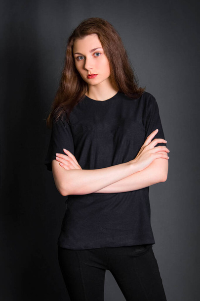 Beautiful, young woman with long hair, in black clothes, posing in studio on a gray background. A model with clean skin. - 写真・画像