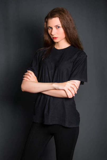 Beautiful, young woman with long hair, in black clothes, posing in studio on a gray background. A model with clean skin. - Foto, Imagen
