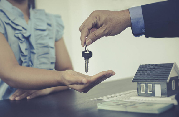 Értékesítési vezető vagy ingatlanügynök birtokolja a kulcsot átadja az ügyfélnek, miután aláírta a lakásbiztosítással, jelzáloggal és biztosítási koncepcióval kötött lakásvásárlási szerződést.. - Fotó, kép
