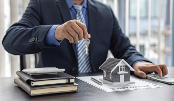 Kierownik sprzedaży lub agent nieruchomości przygotowuje się do przekazania kluczy i domu wraz z ubezpieczeniem do klienta, Uwaga na usługi nieruchomości i koncepcji ubezpieczenia. - Zdjęcie, obraz