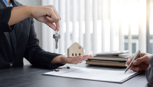 Менеджер з продажу або агент з нерухомості тримає ключ передачі його клієнту після підписання договору купівлі будинку з домашнім страхуванням, торгівлі іпотекою та страховою концепцією
. - Фото, зображення