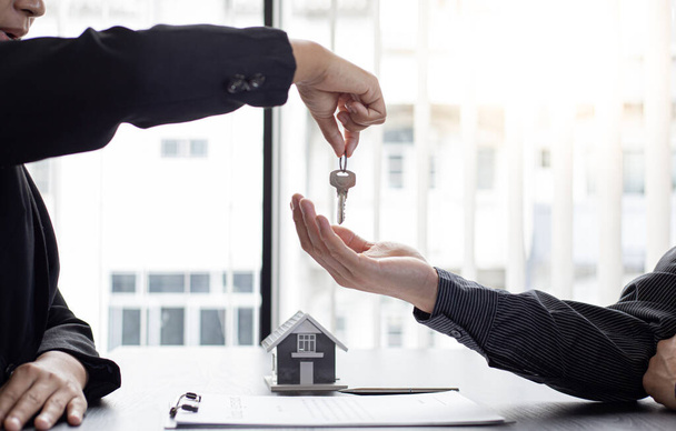 Sales manager or real estate agent holds the key handing it to the customer after signing the house purchase contract with home insurance, Trading of mortgages and insurance concept. - Valokuva, kuva