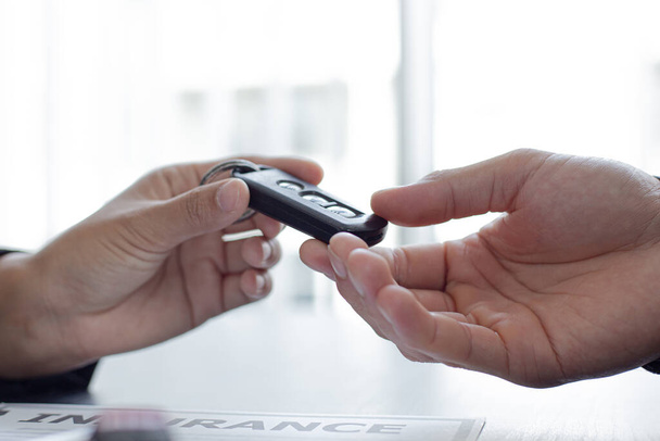 Car sales representative or sales manager submits a car key to a client who has approved financial loans with the company, Approval of financial and banking loans concept. - Fotoğraf, Görsel