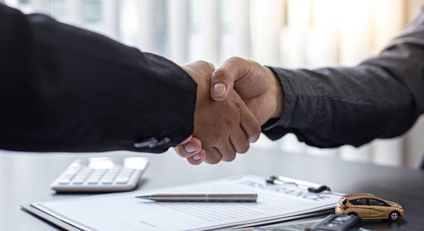 Car dealers or insurance dealers shake hands to congratulate the customers who have signed the car purchase contract with insurance, Shaking hands with success concept. - Photo, Image