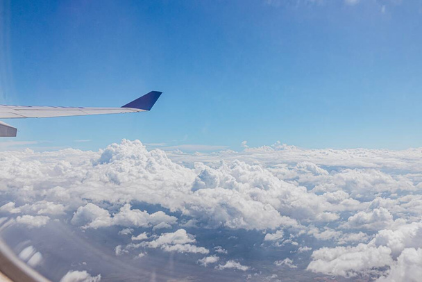 A view of clouds and a wing of an airplane seen through from a glass window - Foto, afbeelding