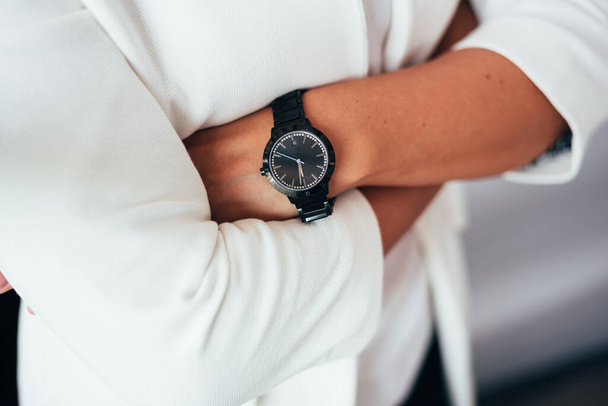 folded arms of a woman in a white shirt with a black watch - Foto, Imagen