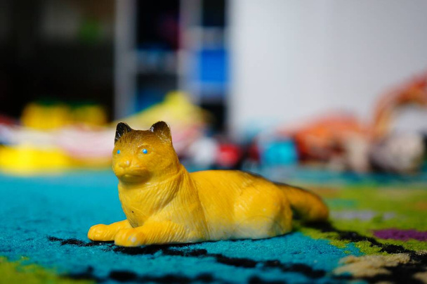 A closeup of a yellow toy lying on a colorful carpet under the lights with a blurry background - Foto, afbeelding