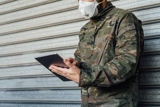 Людина з медичною маскою працює на планшеті під час пандемії Коронавіруса. - Фото, зображення