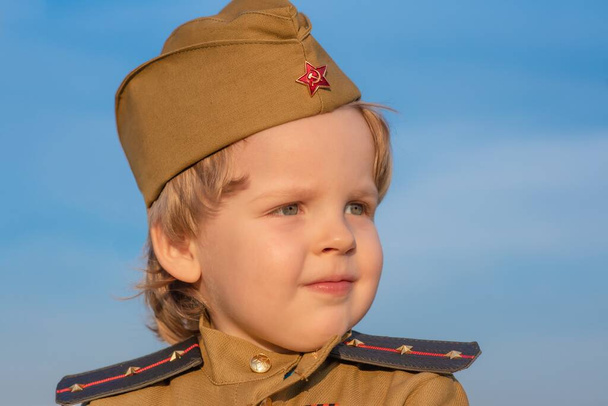 Photo of the son of the regiment, where the boy stands in the military uniform of the Soviet Union in honor of the Russian holiday on may 9 - Foto, Bild