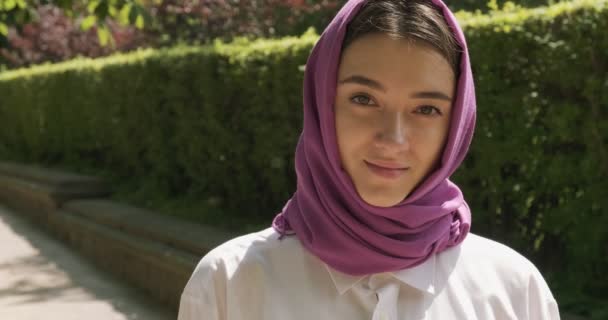 Mooie jonge vrouw die naar de camera kijkt en een traditionele hoofddoek draagt. Aantrekkelijk vrouwtje in hijab - Video