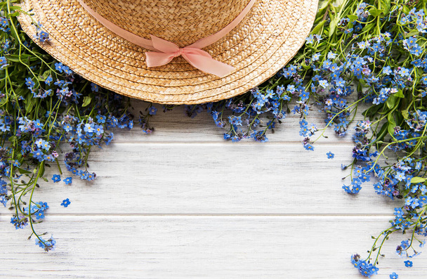 Summer background, a bouquet of forget-me-nots and a straw hat, flat lay - Photo, Image