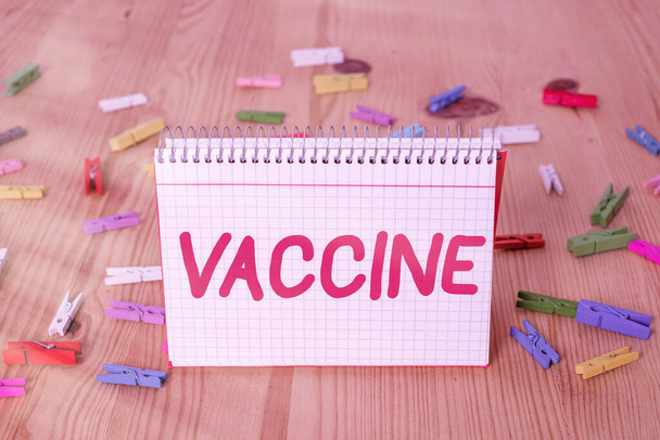 Handwriting text writing Vaccine. Concept meaning preparation of killed microorganisms or living attenuated organisms Colored clothespin papers empty reminder wooden floor background office. - Photo, Image