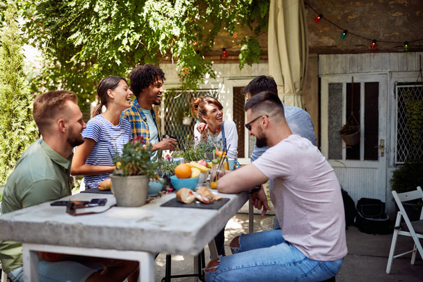 Vriendengroep genieten van een vrolijk gesprek in café 's tuin - Foto, afbeelding
