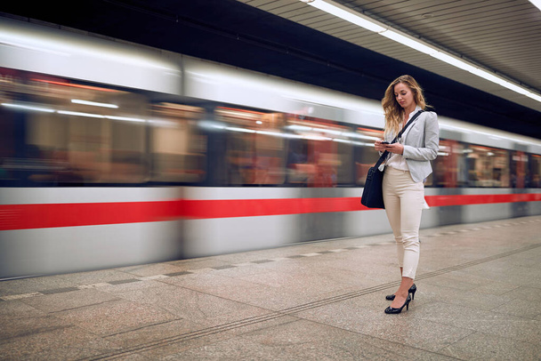 Businesswoman casually waiting for a metro transport on a station - Fotó, kép