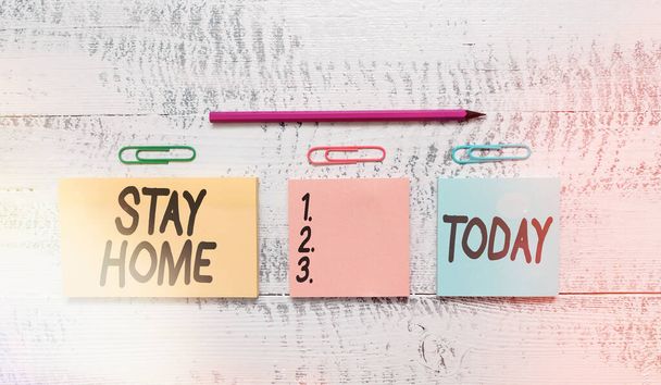 Text sign showing Stay Home. Conceptual photo not go out for an activity and stay inside the house or home Multicolor blank notepads clips marker pencil wooden vintage background. - Fotografie, Obrázek