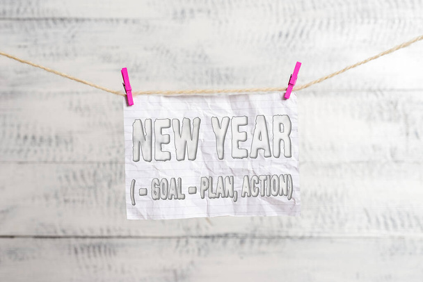 Handwriting text writing New Year Goal Plan, Action. Concept meaning Business solution and planning with motivation Clothesline clothespin rectangle shaped paper reminder white wood desk. - Photo, Image
