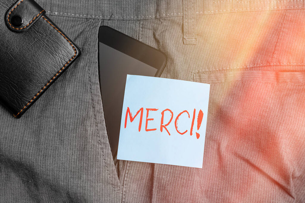 メルシーを示す概念的な手書き文字。ビジネスフォトテキストは、フランス語で誰かが財布とズボンのフロントポケット内のフランスのスマートフォンデバイスであなたを助けるときに言われていることに感謝. - 写真・画像