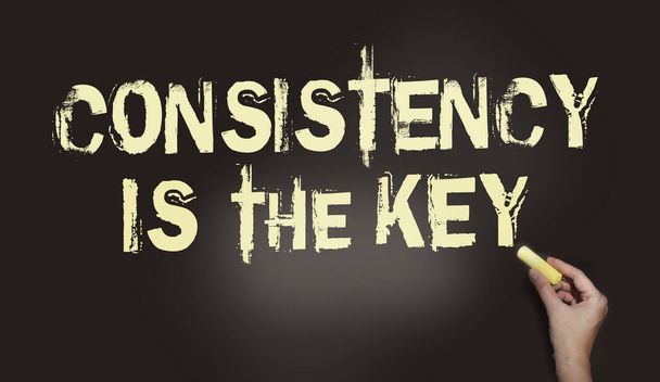 Consistency is the Key chalkboard with text and hand holding piece of cahlk. Business success concept. - Photo, Image