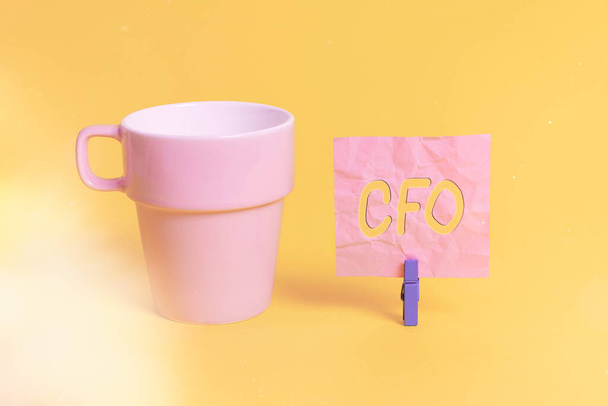 Cfoを示すテキスト記号。会社の財務活動を管理する概念的な写真の最高財務責任者カップ空の紙青の布の長方形型リマインダー黄色のオフィス. - 写真・画像