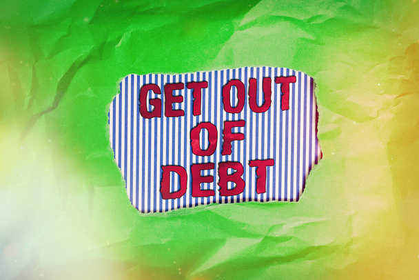 借金から抜け出すことを示す概念的な手の書き込み。変化する支出習慣を紹介するビジネス写真予算を優先する債務を学ぶ緑がかった色の紙シートがカラフルな背景を引き裂いた. - 写真・画像