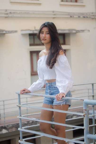 Портрет тайской взрослой красивой девушки Белая рубашка синие джинсы расслабиться и улыбаться
 - Фото, изображение